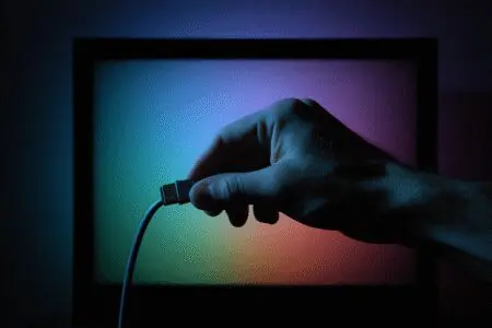 Ruka koja spaja kabel u TV nakon čega se pojavljuje slika kao rješenje za kako vratiti sliku na TV