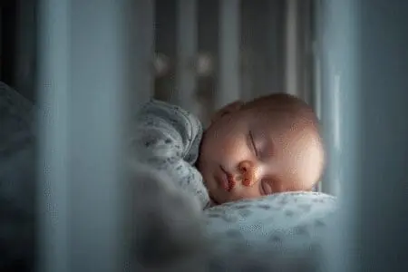 Slika bebe koja mirno spava u krevetiću kao odgovor na pitanje kako uspavati bebu koristeći provjerene metode za miran san