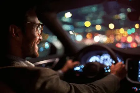 Osoba vozi automobil noću kroz grad kao ilustracija za kako postati Uber vozač