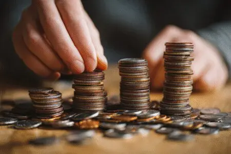 Ruke dijele hrpu novca na tri dijela kao vizualni prikaz za kako složiti plaću od bruto do neto iznosa