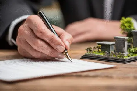 Ruke potpisuju dokument ispred modela grobnog mjesta kao vodič za kako kupiti grobno mjesto