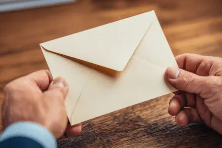 Ruke stavljaju pismo u kuvertu kao primjer za kako napisati molbu za posao