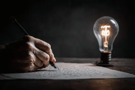 Upaljena žarulja iznad osobe koja piše pismo kao simbol za kako napisati motivacijsko pismo