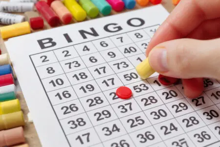 bingo listić na kojem ruka označava pobjednički broj prikazujući trenutak dobitka u igri