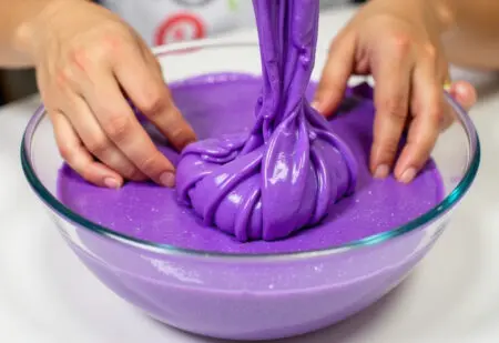 fotografija koja prikazuje kako napraviti slime s dječjim rukama koje miješaju ljepljivu sjajnu smjesu