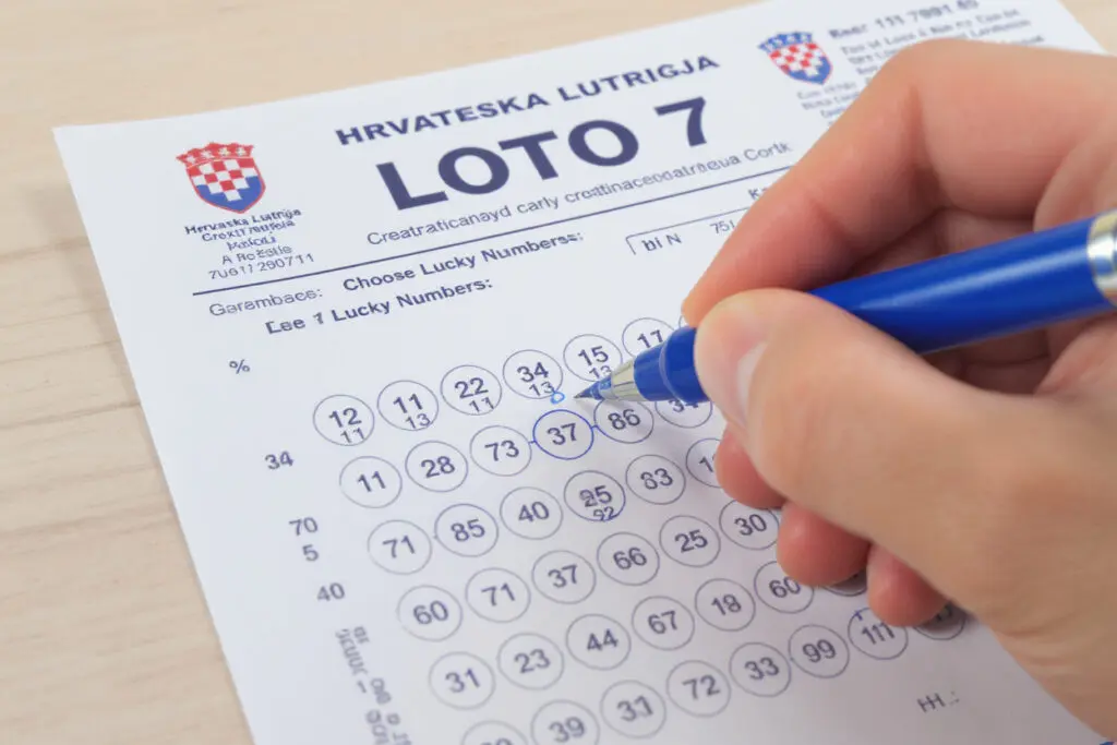 osoba koja kemijskom olovkom ispunjava loto listić birajući svoje sretne brojeve osoba koja kemijskom olovkom ispunjava loto listić birajući svoje sretne brojeve
