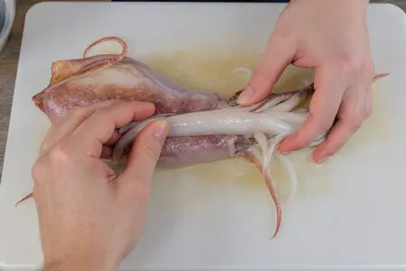 prikaz kako očistiti lignje s fokusom na korak vađenja prozirne kosti iz tijela lignje