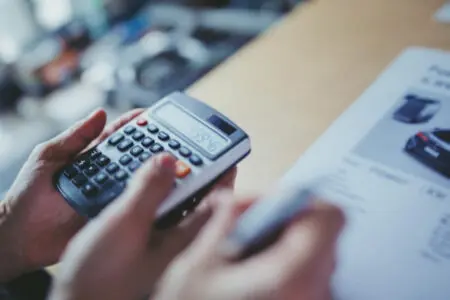 ruke s kalkulatorom pored tehničkih specifikacija vozila simbolizirajući izračun cijena osiguranja vozila po kw