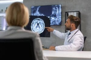 Neurokirurg pokazuje pacijentu snimku magnetske rezonancije mozga