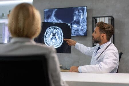 Neurokirurg pokazuje pacijentu snimku magnetske rezonancije mozga