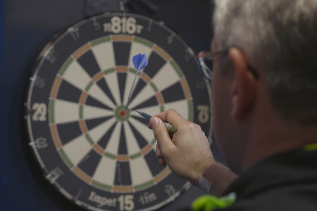 pogled preko ramena igrača koji cilja i sprema se baciti strelicu u pikado metu
